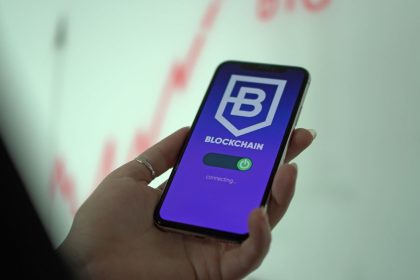 Mão segurando um smartphone com uma carteira digital de criptomoedas exibida na tela.