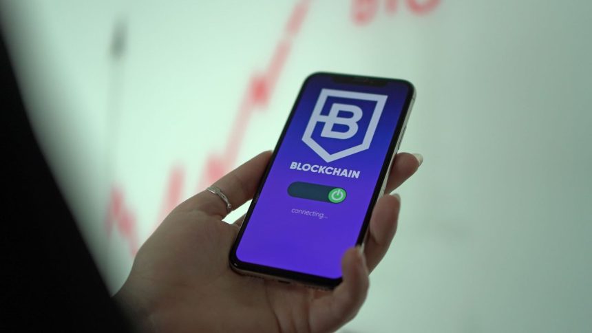 Mão segurando um smartphone com uma carteira digital de criptomoedas exibida na tela.