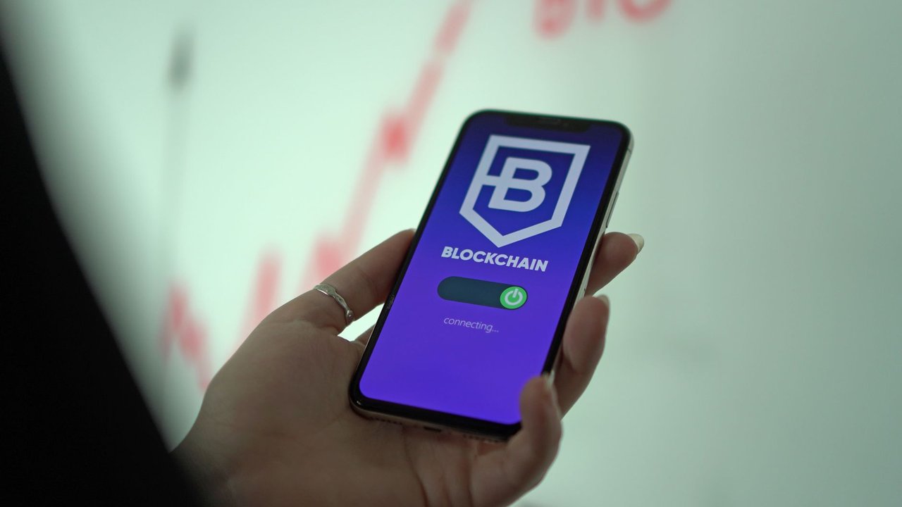 Mão segurando um smartphone com uma carteira digital de criptomoedas exibida na tela.