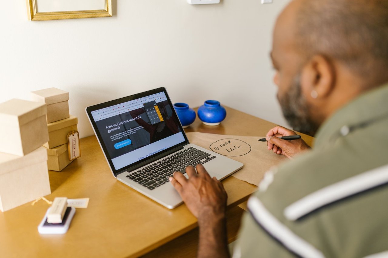 Empreendedor trabalha em um laptop à mesa, em um ambiente de escritório.