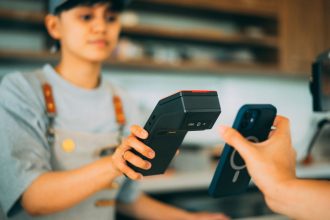 Caixa realiza um pagamento por aproximação com smartphone e leitor de cartões em uma loja