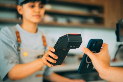 Caixa realiza um pagamento por aproximação com smartphone e leitor de cartões em uma loja