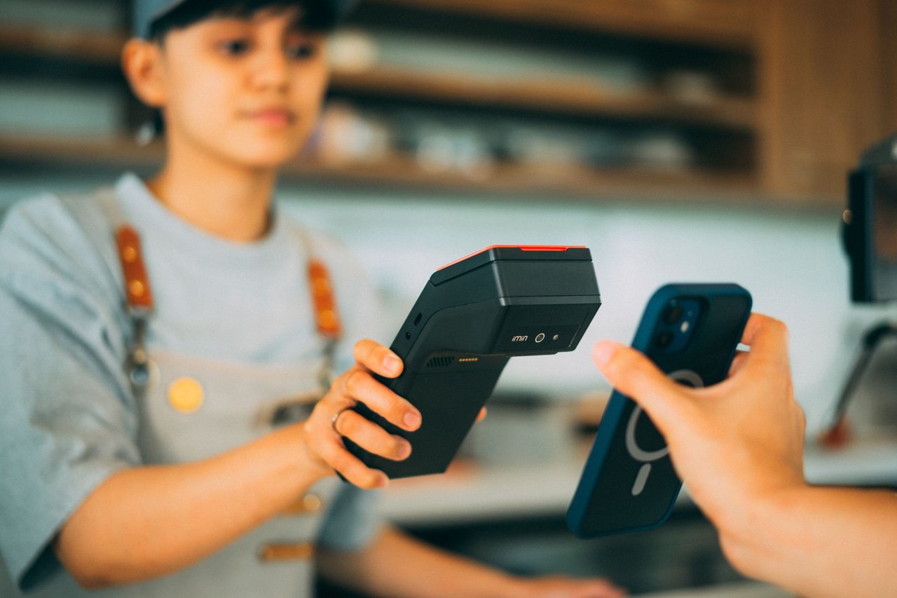 Caixa realiza um pagamento por aproximação com smartphone e leitor de cartões em uma loja
