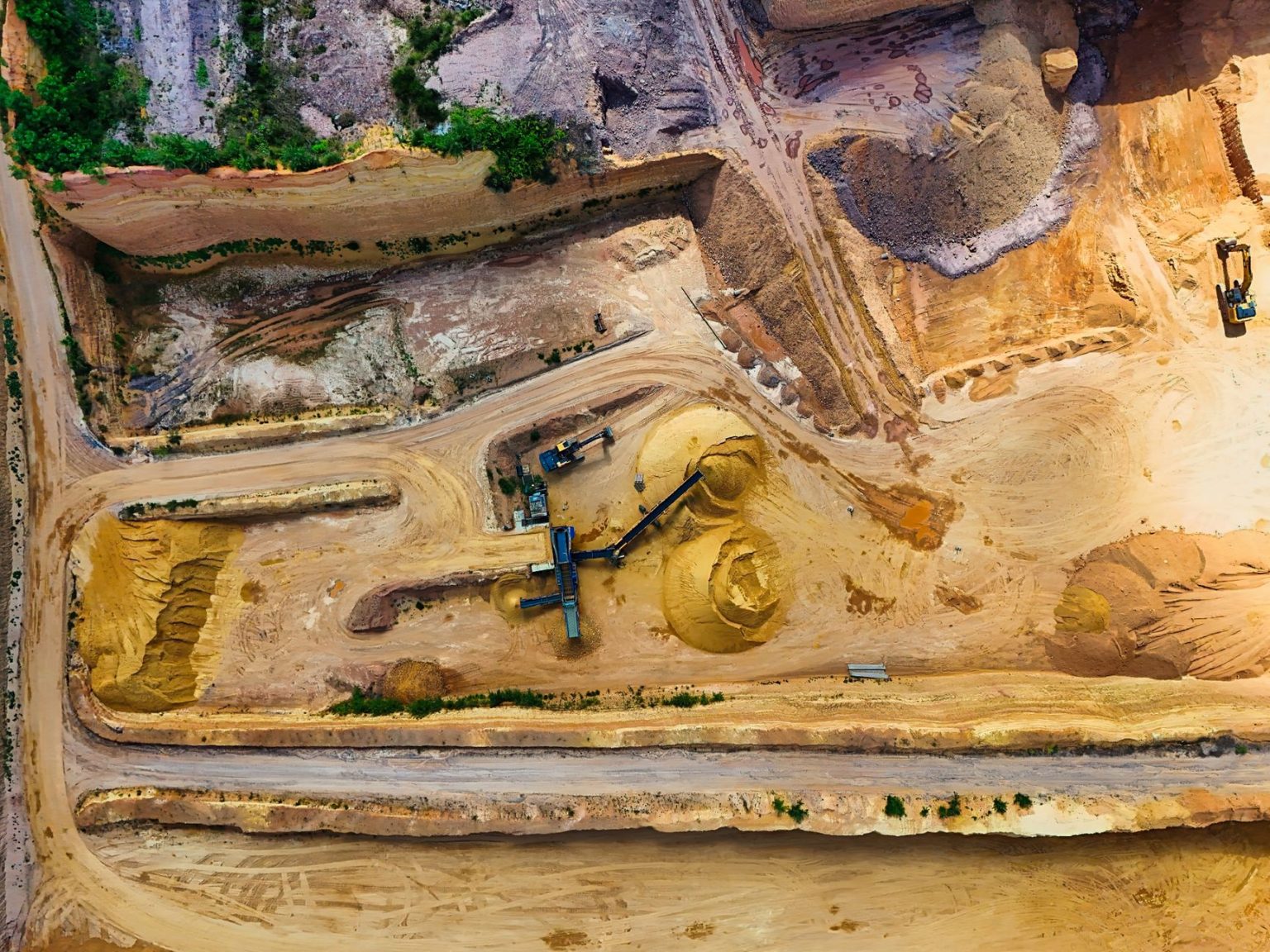 Vista aérea de uma pedreira com máquinas trabalhando na extração e no processamento de materiais minerais