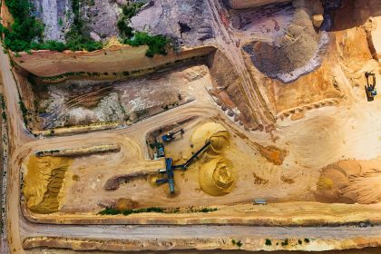 Vista aérea de uma pedreira com máquinas trabalhando na extração e no processamento de materiais minerais